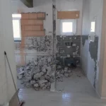 Das Bild zeigt eine abgebrochene wand, die Trümmer liegen noch herum.